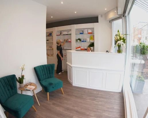 Hove clinic reception area with white desk, product display shelves, green chairs, and bright natural light creating a welcoming, modern space.