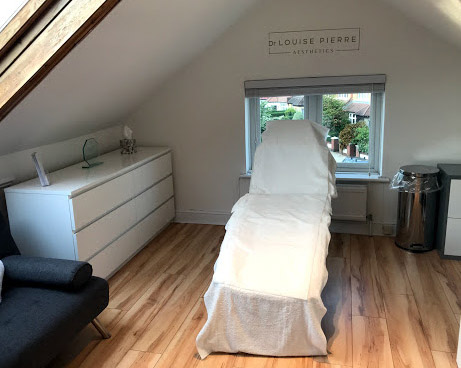 Streatham clinic treatment room with treatment bed by window, wooden flooring, white storage unit, and soft natural light creating a clean, welcoming space.